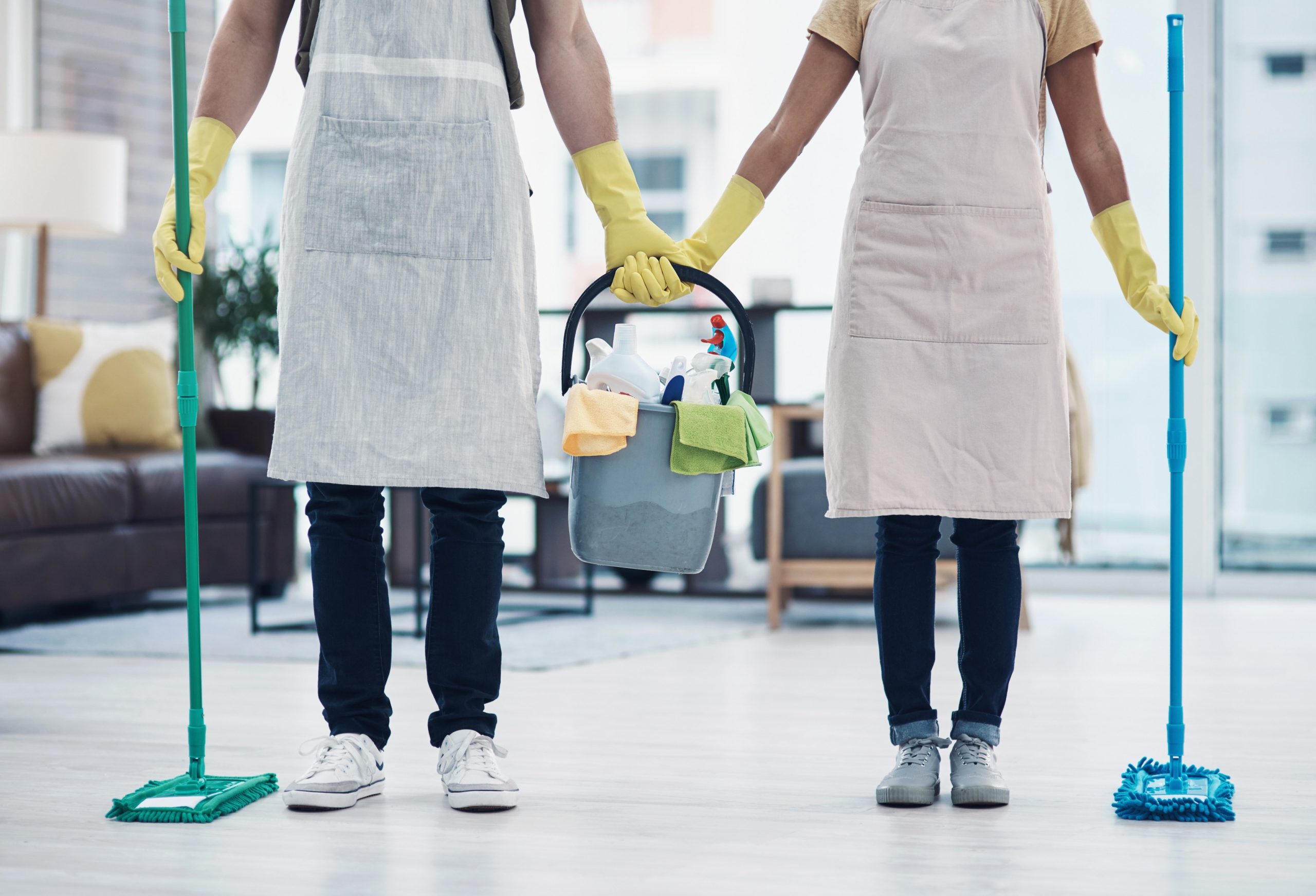 Best Maid Services in Dubai 3 Two cleaners holding mops and a bucket with cleaning supplies in a modern home.